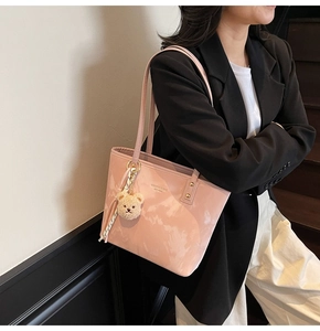 Detailed close-up of pink glossy tote bag with stylish silk scarf and cute bear charm accessory