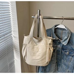 Close-up of beige nylon tote bag with drawstring texture and wide fabric shoulder strap