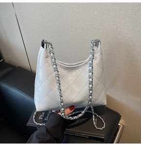 Detail der weißen gesteppten Hobo-Bag mit silberner Kette auf einem Designerbuch