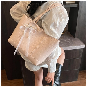 Detail of pink embossed leather tote bag with lace pearl bow and fashion brand label