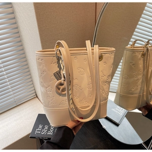 Dettaglio del motivo floreale e orsetto a sbalzo su borsa tote in ecopelle crema con nastro