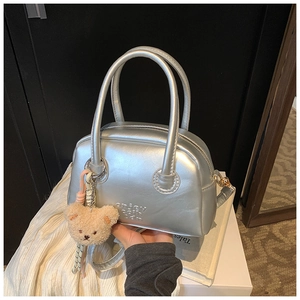 Détail du sac Boston argenté métallisé avec texte gaufré et breloque ours en peluche