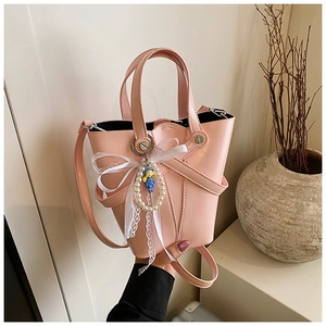 Sac seau rose en similicuir huilé avec pendentif perle et nœud en dentelle blanche