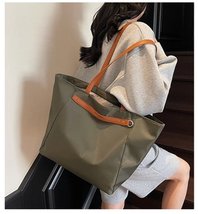 Close-up of olive green oxford tote bag with brown leather strap handles for daily commute