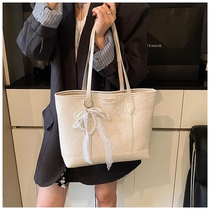 Detail of off-white embossed leather tote with lace pearl bow charm and metal logo