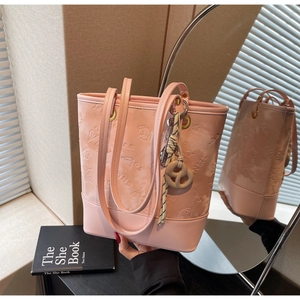 Dettaglio della borsa tote rosa con motivi a rilievo e ciondoli chic in primo piano