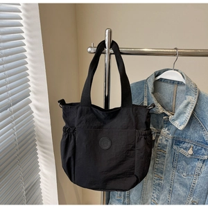 Detail of black nylon tote bag with dual straps and drawstring side pockets on hanger