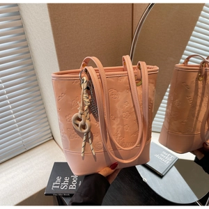 Dettaglio della borsa tote rosa goffrata con motivi a cartoni e un ciondolo artistico