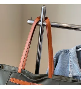 Detail view of the smooth long leather shoulder strap and premium dark green fabric texture