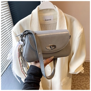 Détail du sac sous le bras en cuir PU gris avec fermoir rotatif argenté et breloques décoratives