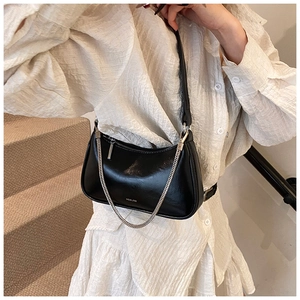 Foto de estilo callejero de bolso sobaquero de cuero negro brillante con cadena de plata