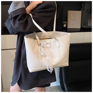 Detail of cream tote bag with floral embossing, lace bow, and pearl pendant accent