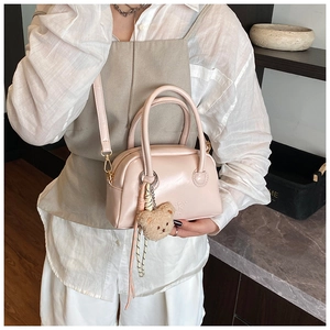 Mini sac Boston rose avec breloque ours en peluche tenu par un mannequin en blanc