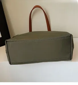 Detail view of reinforced rectangular bottom and stitching on military green nylon tote bag