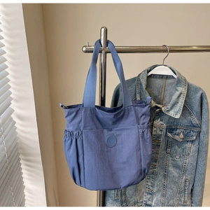 Close-up of blue nylon tote bag with functional side pockets and embossed logo detail