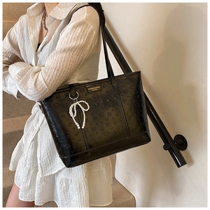 Detail of black faux leather tote with bear embossing and a pearl bow charm