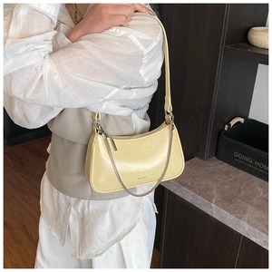 Primer plano de bolso de hombro en cuero amarillo claro con cadena de plata y grabado
