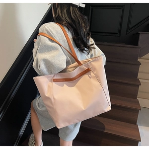 Close-up of pink water-resistant nylon tote bag with brown leather straps for travel