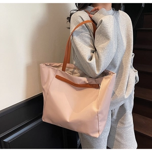 Close-up of pink nylon tote bag with brown leather straps and zip closure on shoulder