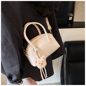 Détail du sac Boston en cuir blanc crème avec lettres gaufrées et charme d'ours en peluche