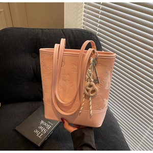 Dettaglio della borsa tote rosa in pelle PU con motivi a rilievo e ciondolo intrecciato