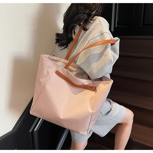 Close-up of pink nylon tote bag with brown leather straps shown on model shoulder