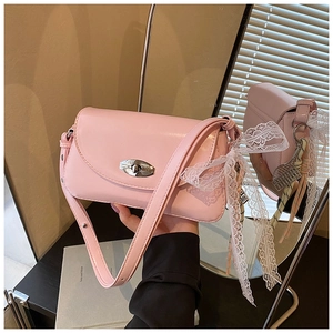 Détail du sac à bandoulière rose clair avec fermoir ovale et nœud en dentelle