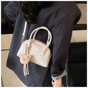 Détail du sac Boston crème en cuir PU avec un charmant ours en peluche marron attaché