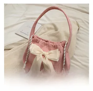 Detailed texture of pink corduroy handbag featuring a large creamy white satin bow accent