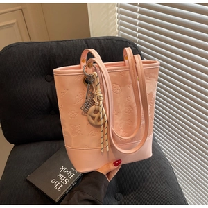 Dettaglio borsa tote rosa goffrata con motivi a cartone animato su sedia di velluto