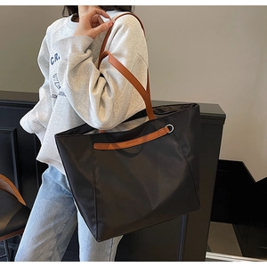 Detail of black oxford tote bag with brown leather straps and silver metal D-ring buckle