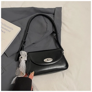 Détail du sac sous le bras noir avec boucle en métal argenté et nœud en dentelle blanche