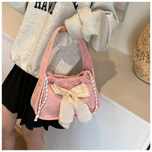 Gros plan du sac en velours côtelé rose orné d'un grand nœud en satin blanc élégant