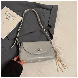 Détail du sac sous le bras gris avec fermoir rotatif et pendentif en dentelle
