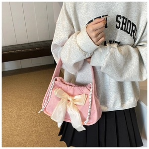 Détail du sac à main en velours côtelé rose avec grand nœud en satin blanc et cordon