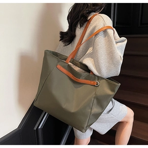 Model showing army green nylon tote bag with brown leather straps on stairs