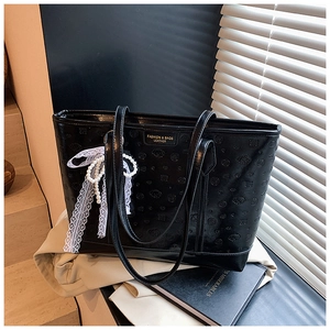 Detail of black tote bag with cartoon embossing, white lace bow, and pearl charm