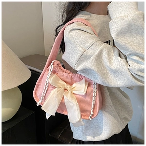 Détail de la texture d'un sac en velours côtelé rose avec nœud en satin crème