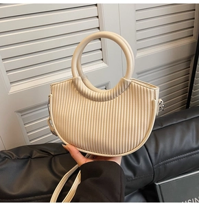 Detail of cream pleated bucket bag showing vertical textures and integrated round handle