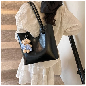 Back view of a glossy black leather bucket bag with a cute bear charm and dmoda logo