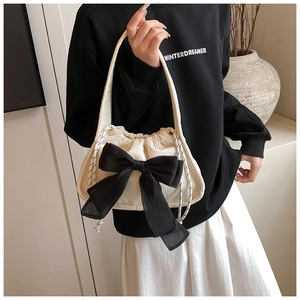 Detail of beige corduroy bag with large black chiffon bow and woven drawstrings