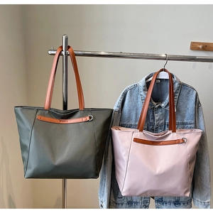 Detail of waterproof nylon tote bags in dark grey-green and pink with leather handles