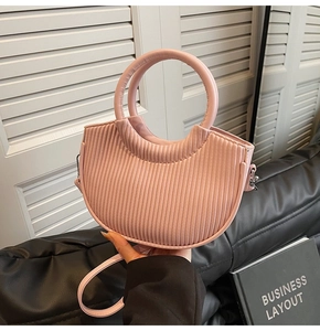 Detail of light pink bucket bag with pleated texture and round handle on modern background