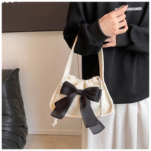 Détail du sac à main en velours blanc avec grand nœud noir et fermeture à cordon