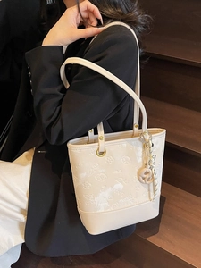 Elegante borsa tote beige con motivi floreali a rilievo indossata da modella