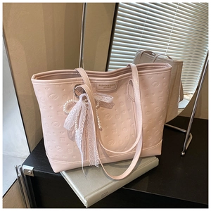 Detail of pink leather tote bag featuring puppy embossing and pearl lace charm