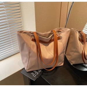 Detail of mauve tote bag showing high-density nylon texture and brown leather handle