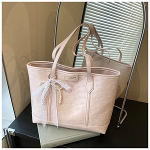 Detail of pink faux leather tote bag with embossed patterns and pearl bow charm