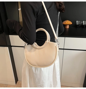 Detailed view of off-white crescent bucket bag with vertical pleated texture and round handle