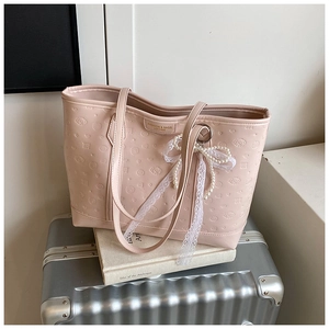 Detailed view of pink tote bag with cartoon embossing and pearl lace bow accessory